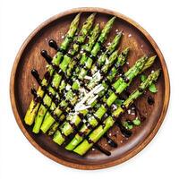 A plate of freshly grilled asparagus, drizzled with balsamic glaze and sprinkled with shaved Parmesan cheese, served on a rustic wooden plate. A simple and flavorful side dish. Isolated on clean white background photo