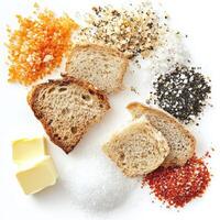 A tasting arrangement of salts from around the world, each with a distinct color and texture, presented with bread and butter, a celebration of the subtle nuances in a fundamental seasoning, isolated on clean white background. photo