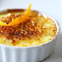A small dish of creme brulee with an orange slice photo