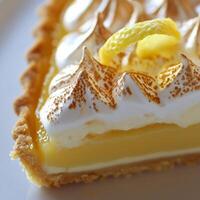 A slice of lemon meringue pie with a lemon wedge photo