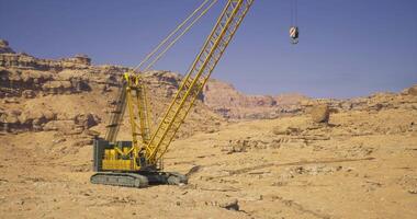 CGI Crane operates in rocky desert environment for construction activities video