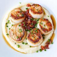 A plate of scallops on top of mashed potatoes photo