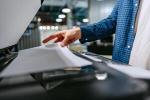 Person using a copier to scan documents in a modern office environment during the day photo