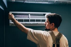 Technician installs air conditioning unit in modern indoor space during warm afternoon photo