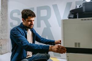 Technologist working with office printer in modern workspace on bright day photo
