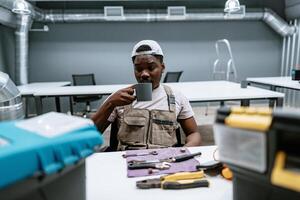 Worker enjoying a coffee break in a modern workshop with tools and equipment around during mid-morning hours photo