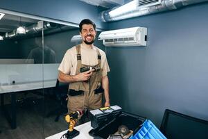 Skilled technician preparing for maintenance work in modern office space with tools at hand during daylight hours photo