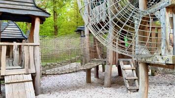 A wooden playground with a rope swing and a slide photo