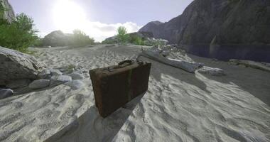 CGI Old suitcase resting on sandy shore under bright sunlight near mountains video