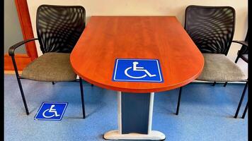 A spacious meeting table designed with accessible seating highlighted by clear wheelchair symbols for inclusivity photo