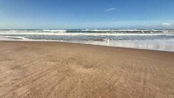 A serene beach scene with gentle waves lapping the shore beneath a bright blue sky and fluffy cotton clouds photo