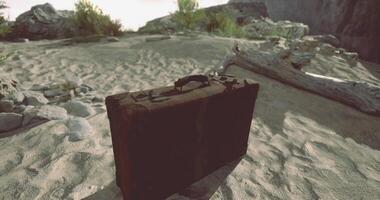 CGI Old suitcase rests on sandy ground near rocky terrain and sparse vegetation video