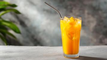 A glass filled with a vibrant yellow drink, ice cubes float within. It's a hot summer day, and this refreshing beverage is ideal for cooling off while enjoying the warm weather at a cafe. photo