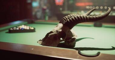 CGI Decorative skull on green billiard table in dimly lit bar setting video