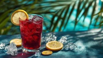 A vibrant glass of iced drink garnished with a lemon slice sits on a table beside a sparkling pool. Nearby, fresh lemon slices and ice cubes add to the refreshing vibe of a sunny summer day. photo