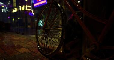 CGI Bicycle rests on wet streets illuminated by neon lights at night video