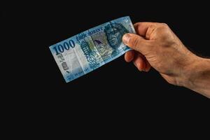 Holding a blue banknote in a hand against a dark background photo
