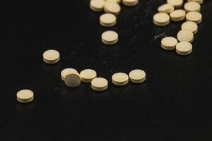 Yellow tablets scattered on a black surface in a clinical setting photo