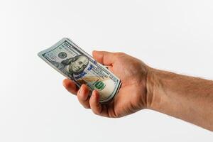 Hand holding a one hundred dollar bill against a plain background photo