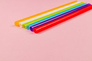 Colorful straws laid out on a pink background for various uses photo