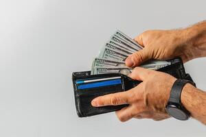 Person counts cash from wallet in a neutral background photo