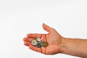 Hand holding various coins against a plain background photo