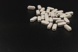 Tablets scattered on a dark surface depicting health supplements photo