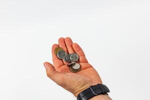 Hand holding various coins against a neutral background photo