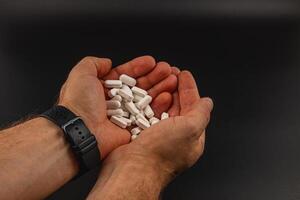 Hands holding white tablets against a dark background photo