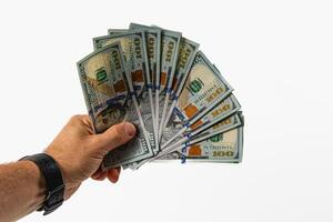 Hand holding several hundred dollar bills on gray background photo