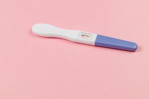 Positive pregnancy test on pink background showing results photo