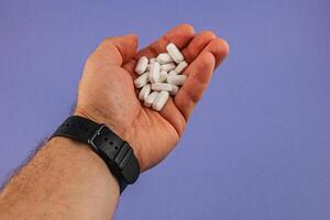 Hand holding white tablets on a blue background photo