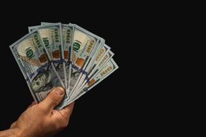 Hand holding bundles of cash against a dark background photo