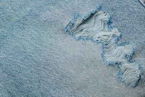 Denim fabric with a visible tear and frayed edges photo