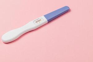 Pregnancy test showing two lines on a pink background photo