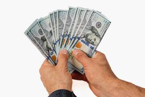 Hands holding a fan of hundred dollar bills in bright light photo