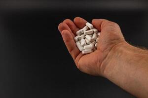 Hand. holding white tablets against a dark background photo