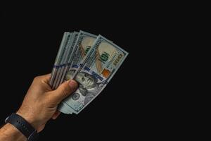 Hand holding cash in a dark setting with focus on bills photo