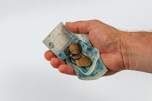 Hand holding cash and coins with currency notes visible photo
