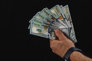 Hand holding hundreds against a black background photo