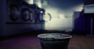 CGI Empty metal bucket placed in a dimly lit laundromat during evening hours video