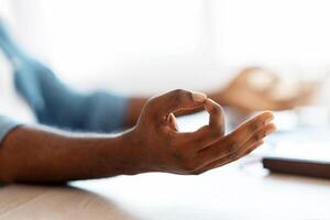 Zen Time. Closeup Shot Of Unrecognizable Black Male Meditating At Desk, African American Man Making Mudra Gesture With Hands, Coping With Stress At Work, Cropped Image With Selective Focus photo