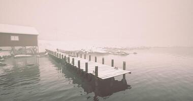 CGI Snowy dock extends into foggy waters near a quiet cabin in winter video