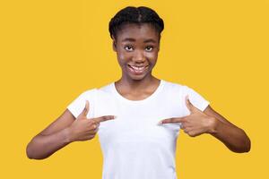 It's Me. Cheerful African American Lady Pointing Fingers At Herself Standing Posing On Yellow Background In Studio. Choose Me Advertisement. Myself And Self-Confidence Concept photo