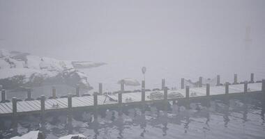 CGI Misty winter harbor with a snowy dock and rocky shores surrounded by fog video