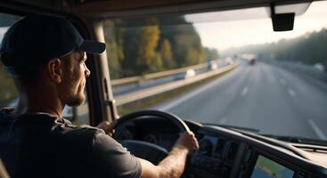 A man drives a large truck on a highway surrounded by trees as the sun sets. The driver focuses intently on the road ahead, embodying the dedication of his profession as he maneuvers through traffic. photo
