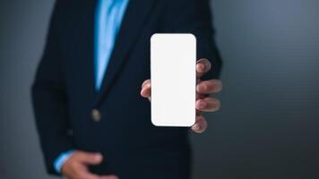 Businessman in a dark suit presents a smartphone with a blank white screen, offering a versatile template for app displays, digital content, or mobile technology concepts. mockup screen phone. photo