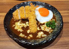 Delicious Curry Dish with Fried Shrimp and Egg on Wooden Table photo