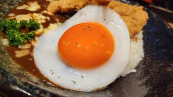 Delicious Japanese Curry Rice with Fried Chicken and Egg Yolk photo