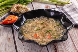 A bowl of soup with a bowl of vegetables and a plate of shrimp photo